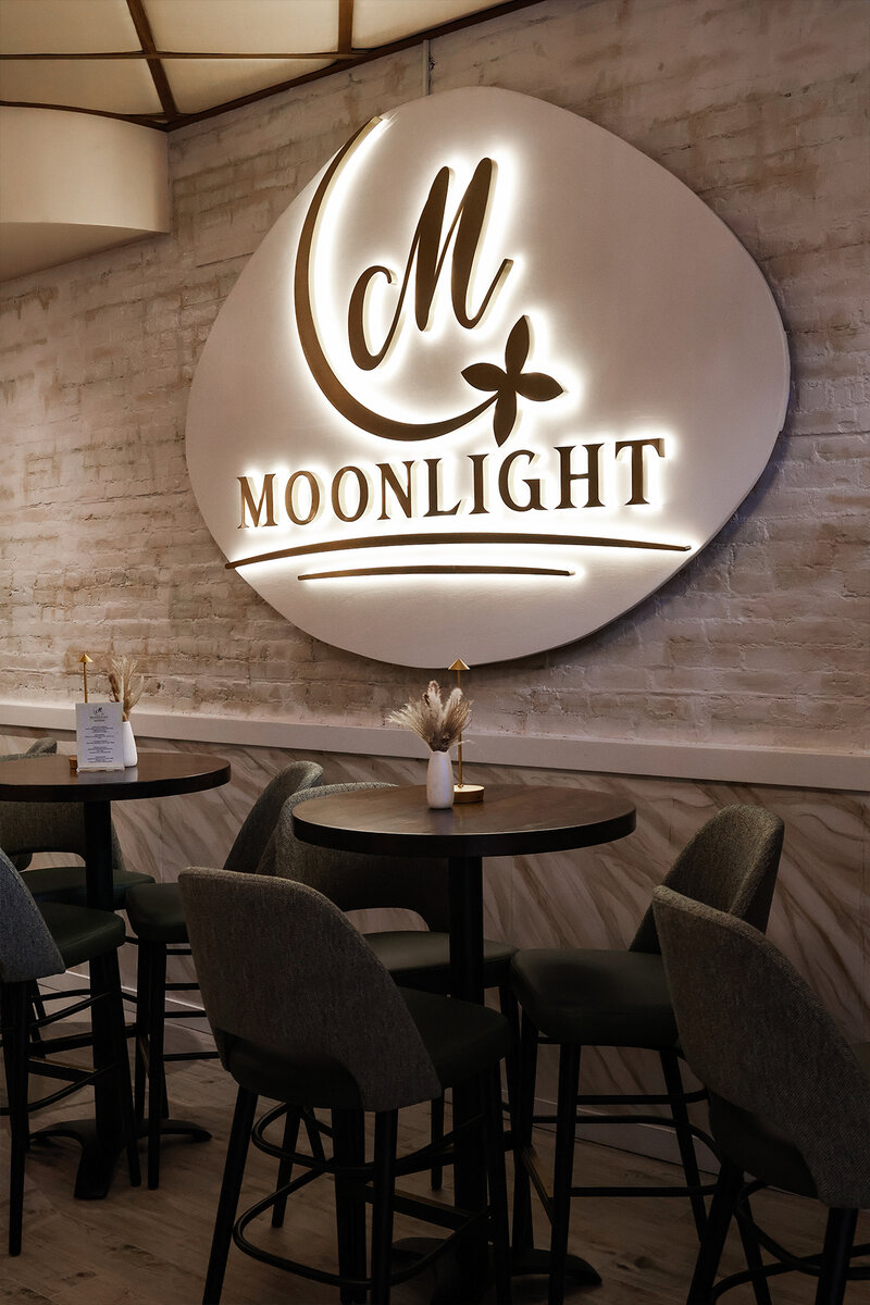 Hightop seating with lit Moonlight sign hanging on wall