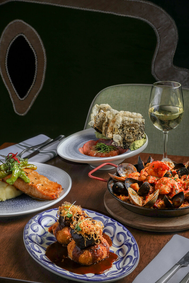 Multiple entrees on set table with glass of white wine